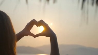 kız kalp elleri deniz arka plan üzerinde yapma. Siluet el gün batımı ile kalp şeklinde içinde. Tatil kavramı. Yaz tatili. Turizm