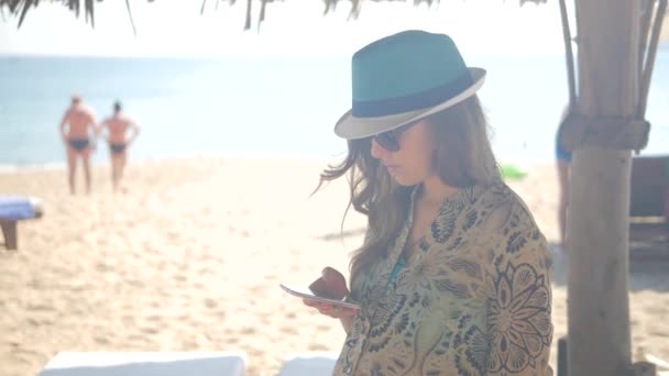 Levensstijl vrouw met behulp van mobiele telefoon op het strand, Handheld schot — Stockvideo