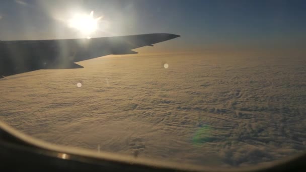 Bulut örtüsü üzerinde uçan bir uçak ışığı üzerinden görüntüleyin. Kanat, mavi gökyüzü ve güneş batmadan görüntülemek