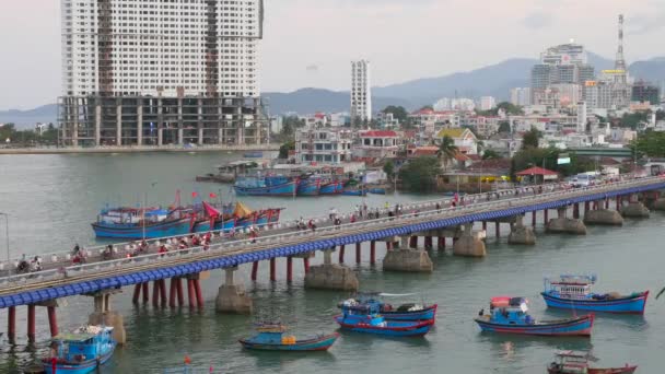 Motorcycle traffic in Nha Trang Bridge, Vietnam. Boats near the bridge. Buildings in the background. — Stock Video