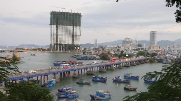 Tráfico en un puente. Bahía de la ciudad con barcos azules y edificios en el fondo. Nha Trang, Vietnam . — Vídeo de stock