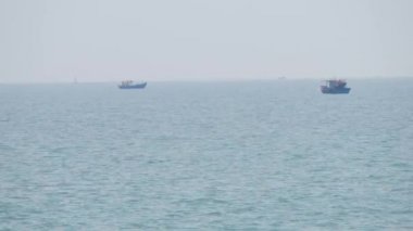 Mavi gökyüzü ve ufuk karşı sakin masmavi deniz boyunca sürüklenen iki Vietnamca tekne