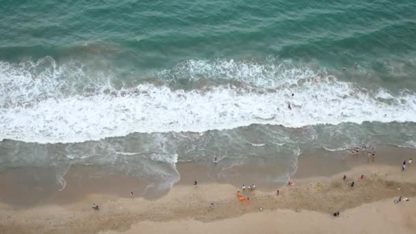 Aerial view of a sandy beach and waving sea. Topview of swimming and walking people. — Stock Video