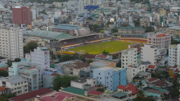 Labdarúgó-mérkőzés egy kis nyitott stadion város épületek között. Légifelvételek. Nha Trang, Vietnam — Stock videók