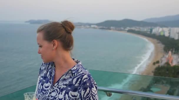 Caucasian girl with glass of juice above the Nha Trang beach at windy evening, Vietnam — Stock Video