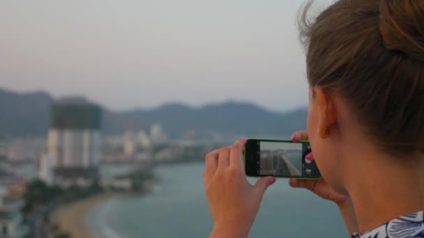 Primer plano de la mujer caucásica tomando fotos de paisaje urbano ser su teléfono inteligente. Nha Trang, Vietnam . — Vídeo de stock