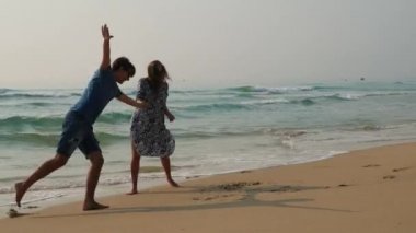 Beautifel mutlu çifti eğlence sahilde palying ve sahip. Hamile kadın erkeğini sarılma