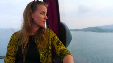 Beyaz kadın günbatımı zaman defne deniz üzerinde Kabin hava Asansör arıyor. Camın önünden geçen başka bir cabing