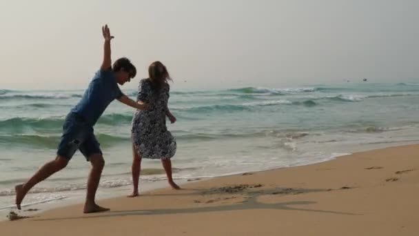 Schöne glückliche Paare, die am Strand bellen und Spaß haben. Schwangere umarmt ihren Mann — Stockvideo