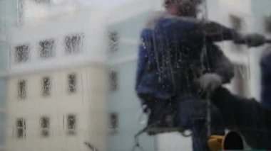Bir duvarda asılı ve pencere yıkama bir adam. Bulanık veiw camı.