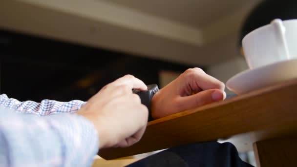 Vue à angle bas des mains masculines tapotant sur l'écran tactile d'une montre connectée — Video