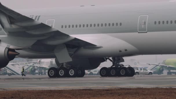 Wielen en turbines van een 777-300er boeing verplaatsen op een baan in de luchthaven. Close-up beeld, mist weer, 4 k Uhd 2160 p — Stockvideo