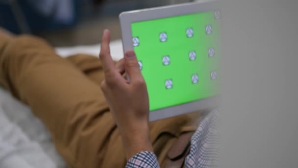 Долли, слайдер снимок планшета в мужских руках стучать пальцами с зеленым экраном, используя площадку на домашнем диване, 4k UHD 2160p — стоковое видео