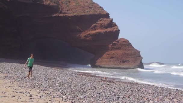 Homem andando na praia legzira com arcos naturais — Vídeo de Stock