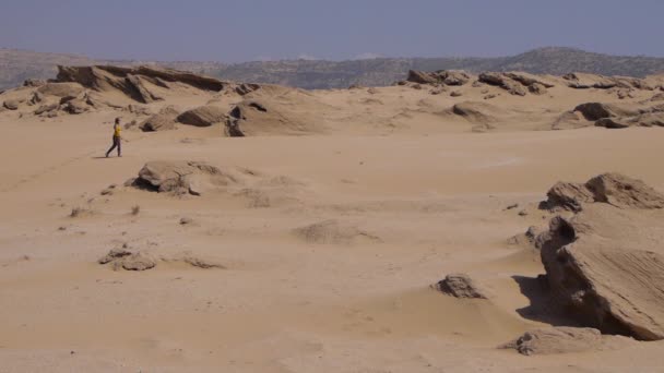Mujer joven caminando sobre hermosas dunas del desierto inspiradoras en el soleado día de verano — Vídeo de stock