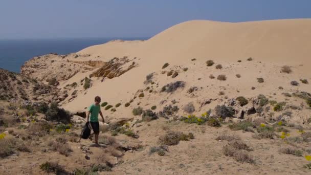 Hombre joven cruza hermosas dunas inspiradoras del desierto en el soleado día de verano — Vídeos de Stock