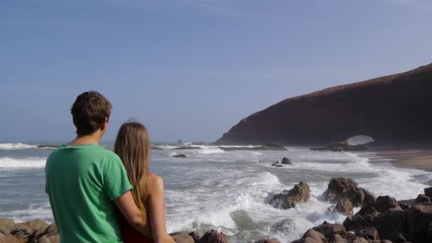 Visão traseira de um casal abraçando e assistindo o mar na praia legzira — Vídeo de Stock