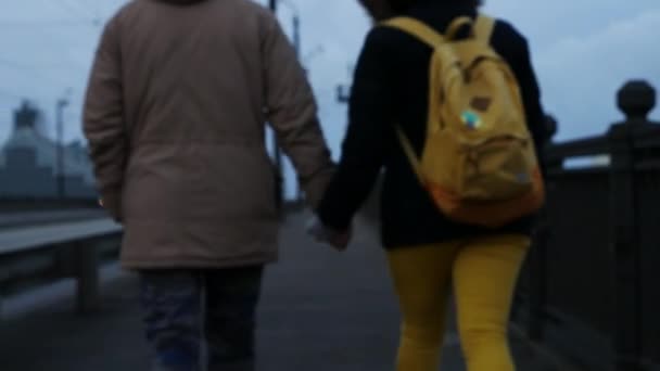 Ζευγάρι περπατά εκμετάλλευση τα χέρια στην πόλη της Ρίγας, Λεττονία, Ευρώπη. Φορητό πυροβολισμό — Αρχείο Βίντεο