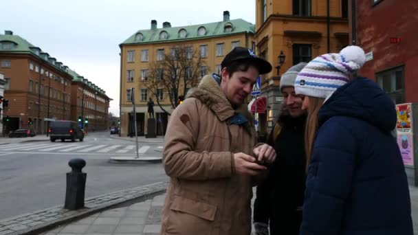 Trzech młodych przyjaciół, patrząc na mapę miasta w smartfonie, planowanie gdzie iść w jego podróży — Wideo stockowe