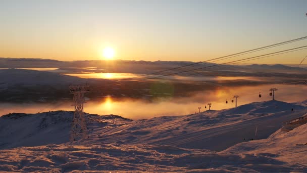 Belle vue sur le téléphérique en mouvement dans les montagnes enneigées au coucher du soleil. Suède — Video