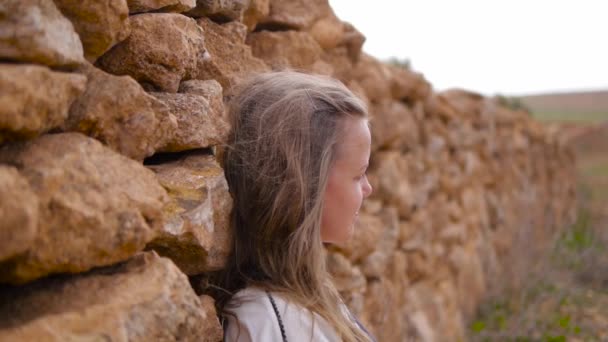 Porträt eines kaukasischen Mädchens gegen eine Steinmauer. — Stockvideo