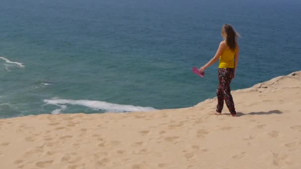 年轻女子穿越沙漠，大海背景 — 图库视频影像