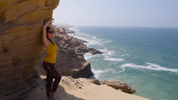 Mulher bonita ficar perto de rocha sobre deslumbrante oceano vista de fundo — Vídeo de Stock