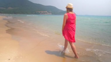 Mayo ve kırmızı tunik su kenarı boyunca yürüyüş içinde bekleyen anne. Vietnam tropikal tatil.