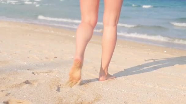 Barfußbeine einer kaukasischen Frau, die auf Sand ins wogende Meerwasser läuft. Dolly in Handschellen — Stockvideo