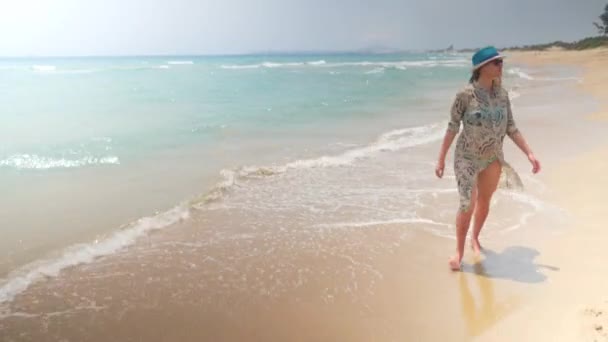 Lächelnde Schwangere am Strand in Badebekleidung, Tunika und blauem Hut — Stockvideo