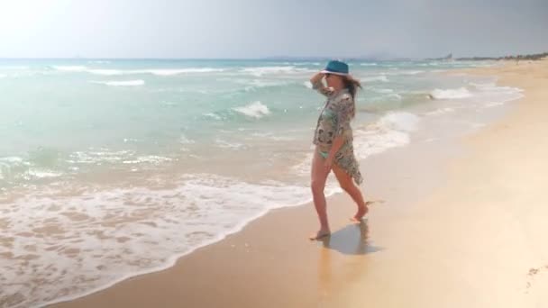 若くてかなり妊娠中の女性が海でビーチの水の端にスキップ — ストック動画