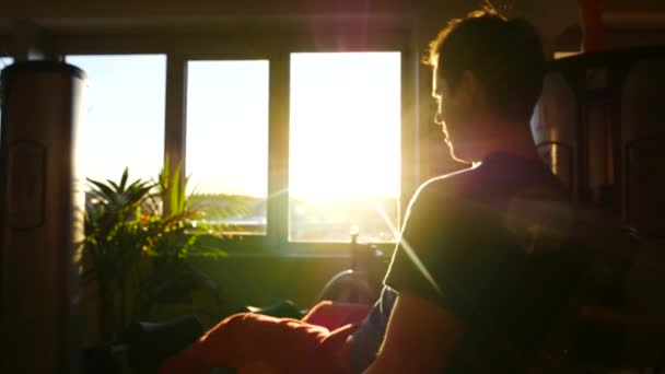 Wazig zicht op een jonge man uit te werken in een sportschool in de stralen van de zon vanuit het venster. Pannen van rechts naar links en terug — Stockvideo