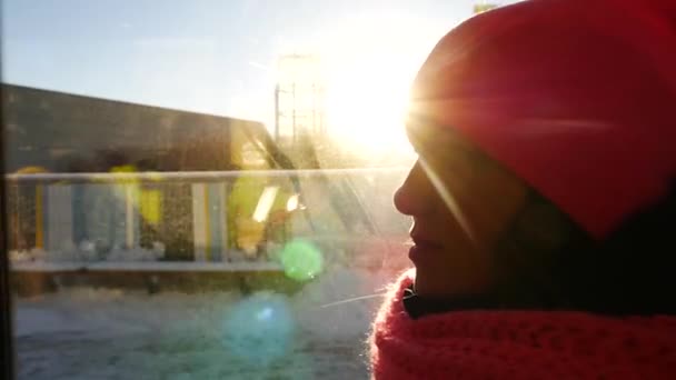 Bella ragazza in berretto rosa cavalcando autobus pubblico. Primo piano del viso alla finestra con raggi di sole e luci — Video Stock