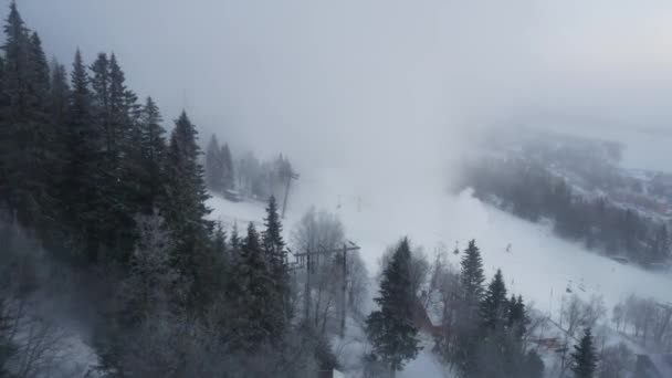 Blick von einer Gondelbahn auf einen Hang und nebligen Wald — Stockvideo