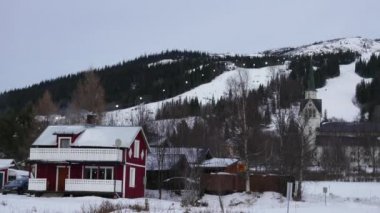 Kayak merkezi İsveç'te yazlık. İz sürme kayaklar insanlarla ve behinde evi snowboard