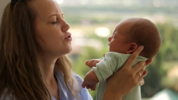 Attraktive Mutter hält Neugeborenes, spricht zärtlich mit ihm und küsst ihm auf die Nase — Stockvideo