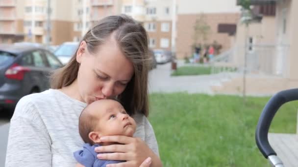 Güzel genç anne sakin bebek üzerinde gülümseyen ve oğlu ile konuşurken silah ile — Stok video