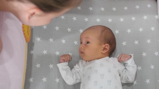 Frau beugt sich über ihr süßes kleines Baby in einer Wiege. Handschuss — Stockvideo