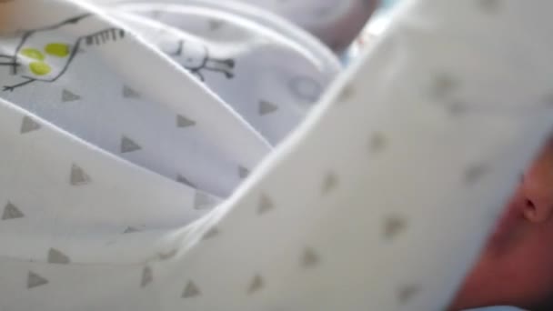 Recién nacido con ropa blanca de bebé acostado en un mal y moviendo las manos — Vídeos de Stock