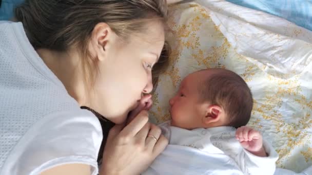 Niedliche Säugling auf einem Bett mit seiner Mutter. junge Frau spricht und küsst ihr Baby — Stockvideo