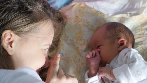 Ung mamma leker med sitt nyfödda barn i ett sovrum — Stockvideo