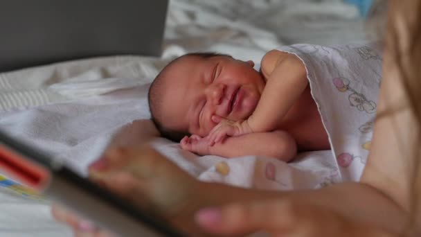 Söt baby sover medan hans mor läser ett använder moderna e-bok. Fokusera på barnet — Stockvideo