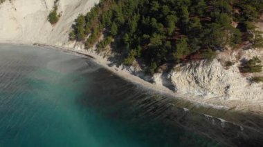 Beyaz tortulu kaya ve deniz kıyısındaki yeşil orman. Şeffaf deniz suyu