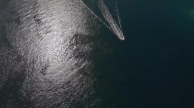 Sürat teknesi parlak sularda yüzer arkasında beyaz izler bırakır. Hava görüntüsü