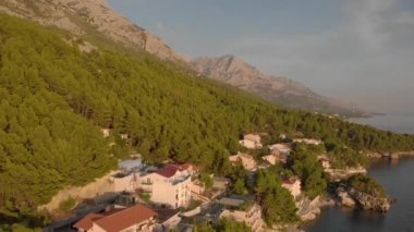Dağın dibindeki sahil kasabası. Orman ağaçlarının arasında evler. Hava görüntüsü