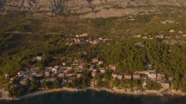Kayalık tepe ve deniz kıyısındaki turistik kasabadan uçarak uzaklaşıyor. Hırvatistan Havacılığı