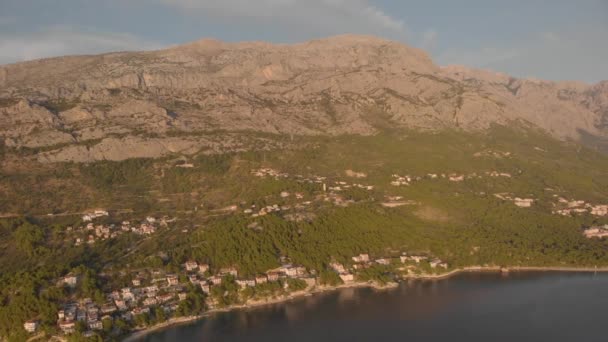 海の湾の上に高い山。緑の森に囲まれた小さな町。空中 — ストック動画