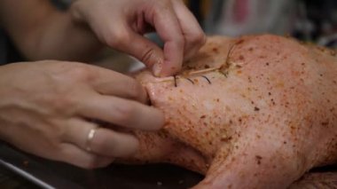 Erkek eller şenlikli yemek için doldurulmuş bir kuşu dikiyor. Tüm kazı hazırlıyorum.