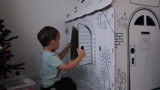 Dětský a papírový dům. Dítě otevře a zavře papírové okno na stěně s písmeny a číslicemi — Stock video