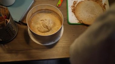 Baker tatlı bir pasta yapar. Kadın kaşık kaşık krem sürüyor. Masanın yüksek açılı görüntüsü